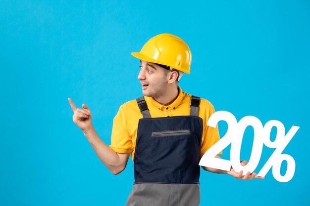 Vista frontale del giovane operaio maschio in uniforme con la scrittura sull'azzurro