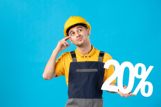 Vista frontale del giovane operaio maschio in uniforme con la scrittura sullo scrittorio blu