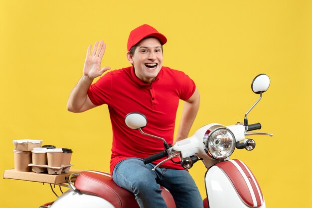 Vista frontale del giovane ragazzo sorridente che indossa la camicetta rossa e il cappello che trasporta gli ordini che mostrano dieci su fondo giallo