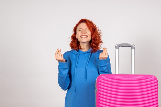 Vista frontale del giovane turista femminile con borsa rosa sul muro bianco