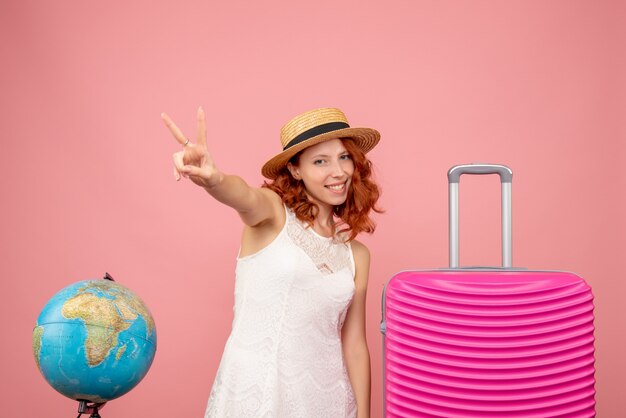 Vista frontale del giovane turista femminile con borsa rosa sulla parete rosa