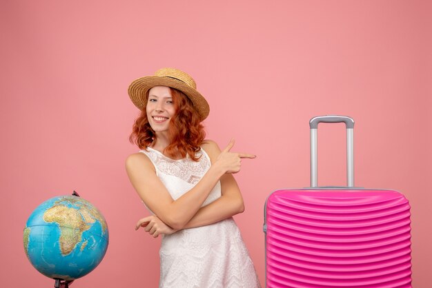 Vista frontale del giovane turista femminile con borsa rosa sulla parete rosa