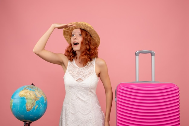 Vista frontale del giovane turista femminile con borsa rosa sulla parete rosa