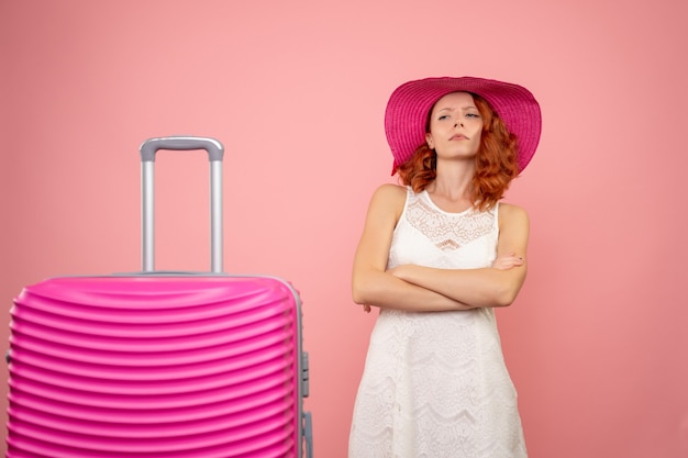 Vista frontale del giovane turista femminile con cappello rosa e borsa sulla parete rosa