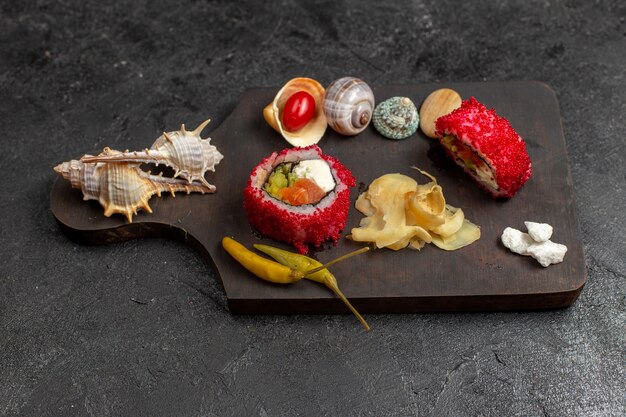 Vista frontale del gustoso sushi pasto affettato involtini di pesce con conchiglie sul muro grigio