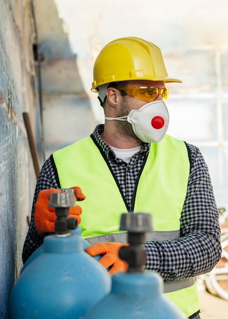 Vista frontale del lavoratore con maschera protettiva e elmetto