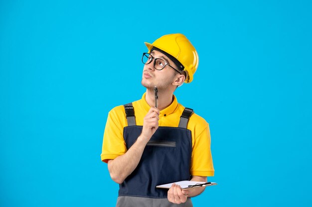 Vista frontale del lavoratore di sesso maschile nelle note di scrittura uniformi gialle sull'azzurro