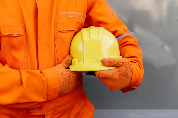 Vista frontale del lavoratore in uniforme che tiene il cappello duro