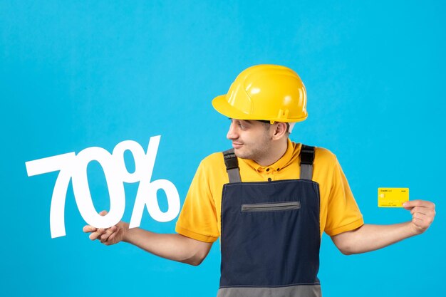 Vista frontale del lavoratore maschio in uniforme con scrittura e carta di credito sull'azzurro