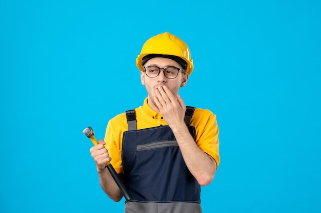 Vista frontale del lavoratore maschio in uniforme gialla sull'azzurro