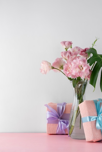 Vista frontale del mazzo di fiori in vaso con scatole regalo