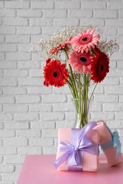 Vista frontale del mazzo di fiori in vaso con scatole regalo