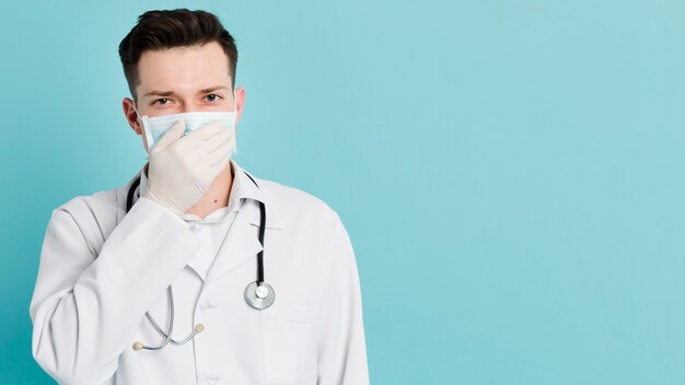 Vista frontale del medico che copre la bocca mentre indossa una maschera medica