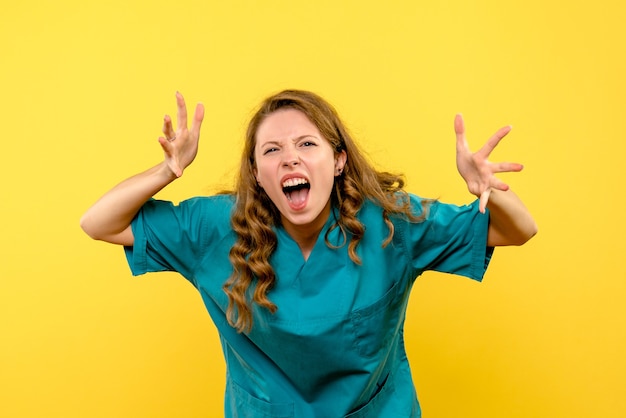 Vista frontale del medico femminile che grida sulla parete gialla