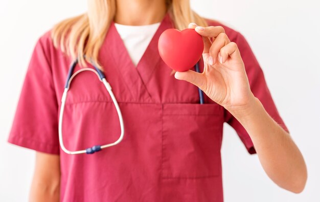 Vista frontale del medico femminile che tiene a forma di cuore