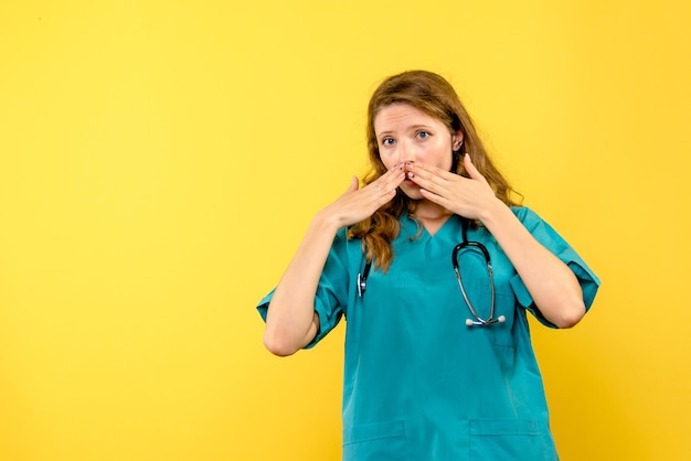 Vista frontale del medico femminile sorpreso sulla parete gialla