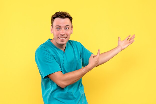 Vista frontale del medico maschio con espressione eccitata sulla parete gialla