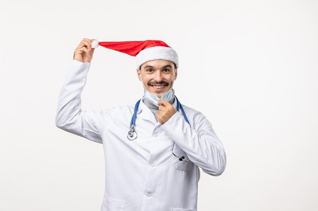 Vista frontale del medico maschio in maschera sul muro bianco