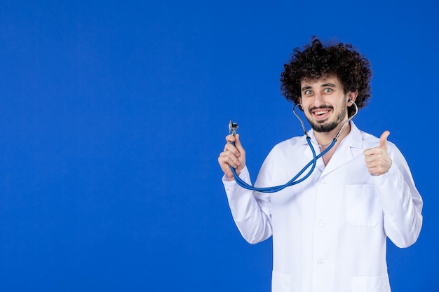 Vista frontale del medico maschio in tuta medica con stetoscopio su sfondo blu virus sanitario ospedale covid- vaccino farmaco pandemico