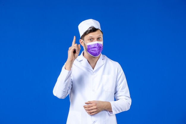 Vista frontale del medico maschio in tuta medica e maschera viola che ha un'idea sull'azzurro