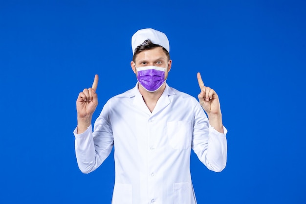 Vista frontale del medico maschio in tuta medica e maschera viola sull'azzurro