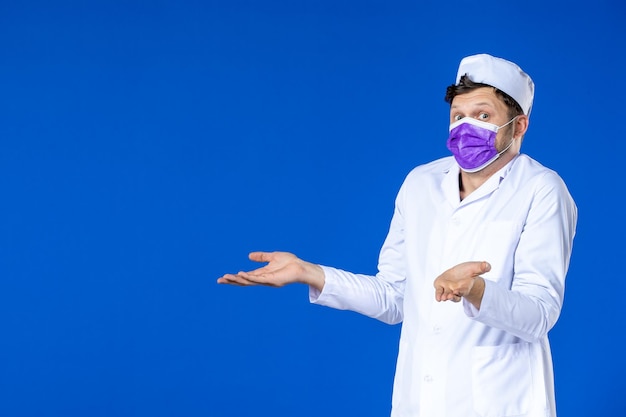 Vista frontale del medico maschio in tuta medica e maschera viola sull'azzurro