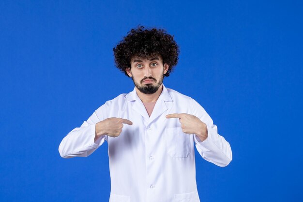 Vista frontale del medico maschio in tuta medica su sfondo blu medicina vaccino vaccino covid- ospedale virus pandemia salute coronavirus colori