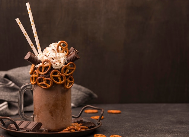 Vista frontale del milkshake al cioccolato con cannucce e salatini