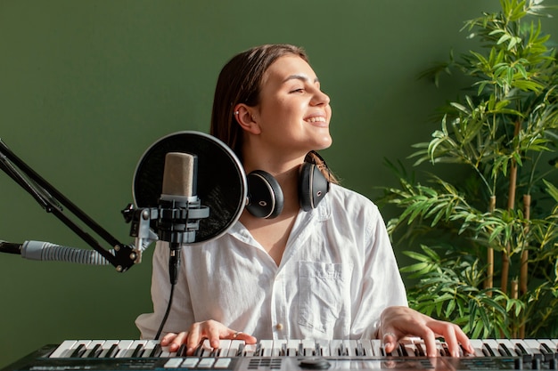 Vista frontale del musicista femminile smiley suonare la tastiera del pianoforte al chiuso