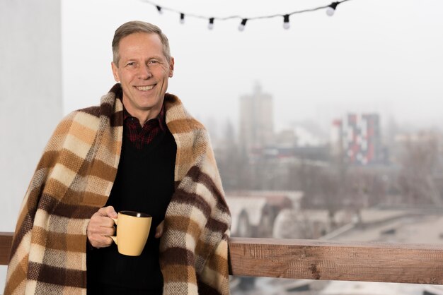 Vista frontale del padre con la coperta che tiene tazza in mano