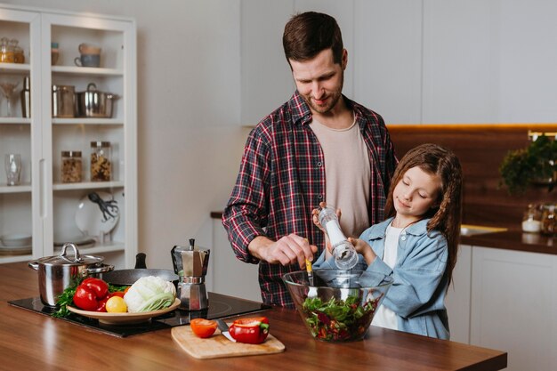 Vista frontale del padre con la figlia che prepara il cibo in cucina