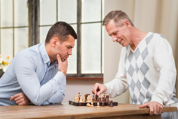 Vista frontale del padre e del figlio che giocano a scacchi