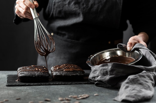 Vista frontale del pasticcere che prepara la torta con il cioccolato