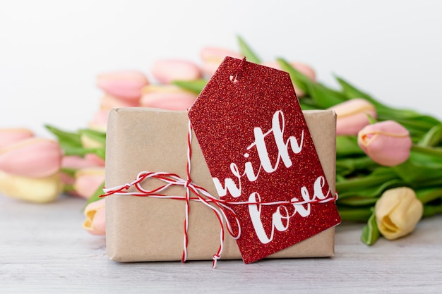 Vista frontale del presente con etichetta e tulipani per San Valentino