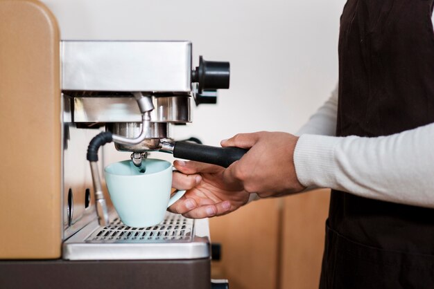 Vista frontale del ragazzo che produce caffè espresso