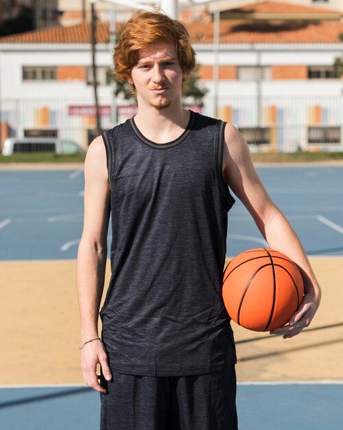 Vista frontale del ragazzo con la palla da basket