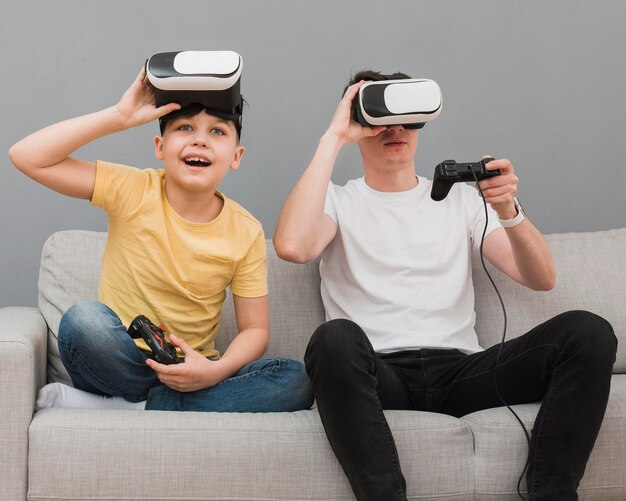 Vista frontale del ragazzo e dell'uomo giocare ai videogiochi con le cuffie da realtà virtuale