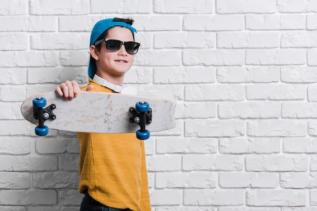 Vista frontale del ragazzo moderno con skateboard