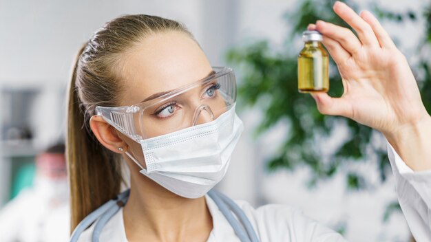 Vista frontale del ricercatore femminile con maschera medica e vaccino