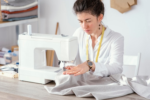 Vista frontale del sarto femminile che lavora con la macchina da cucire