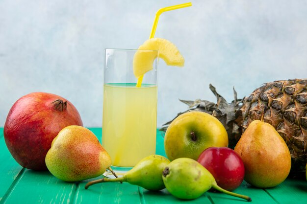 Vista frontale del succo di ananas con mela mela pesca melograno prugna ananas sulla superficie verde e superficie bianca