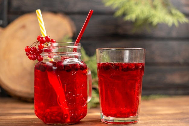 Vista frontale del succo di ribes fresco biologico naturale in una bottiglia servita con tubi e in un bicchiere su un tavolo di legno