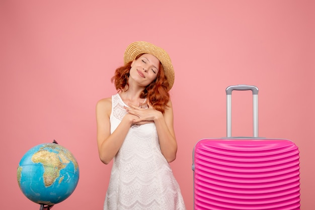 Vista frontale del turista femminile con borsa rosa sulla parete rosa