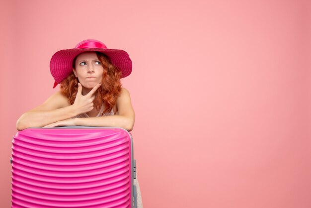 Vista frontale del turista femminile con borsa rosa sulla parete rosa