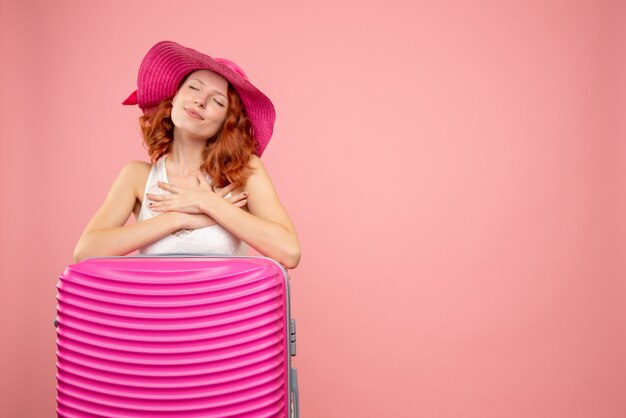 Vista frontale del turista femminile con borsa rosa sulla parete rosa