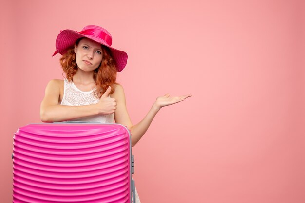 Vista frontale del turista femminile con borsa rosa sulla parete rosa