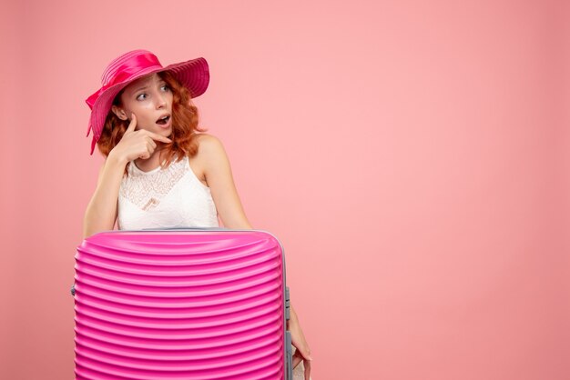 Vista frontale del turista femminile con borsa rosa sulla parete rosa