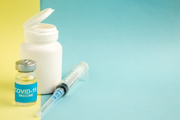 vista frontale del vaccino contro il coronavirus con iniezione su sfondo giallo-blu virus dell'ospedale covid- laboratorio sanitario scientifico colore pandemico spazio libero dalla droga