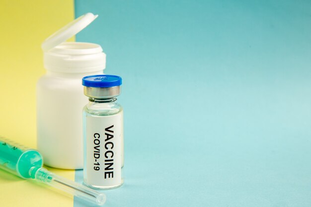vista frontale del vaccino contro il coronavirus con iniezione su sfondo giallo-blu virus dell'ospedale covid- laboratorio scientifico farmaco sanitario pandemia colore spazio libero