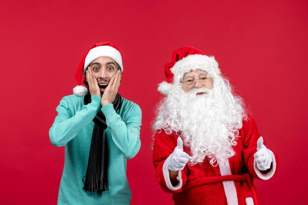 Vista frontale del vecchio babbo natale con uomo in piedi sul muro rosso